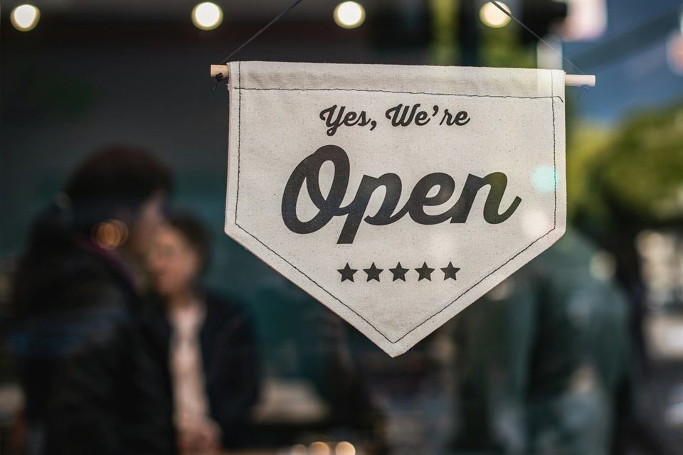 A &ldquo;Yes, we&rsquo;re open&rdquo; sign hanging in a shop